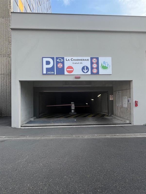 Entrée du parking souterrain La Charmeraie : rampe d'accès avec barrière et panneau « La Charmeraie — Gratuit 2h — 24/24h ».